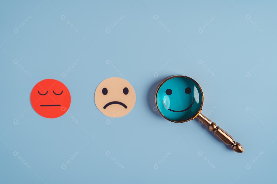 Mão segurando lupa foco selecionado corte de papel de rosto sorridente feliz que está entre várias emoções