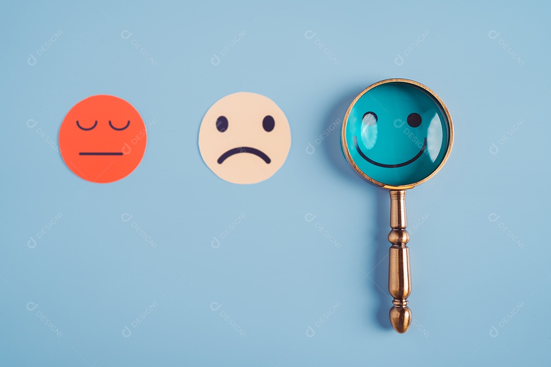 Mão segurando lupa foco selecionado corte de papel de rosto sorridente feliz que está entre várias emoções