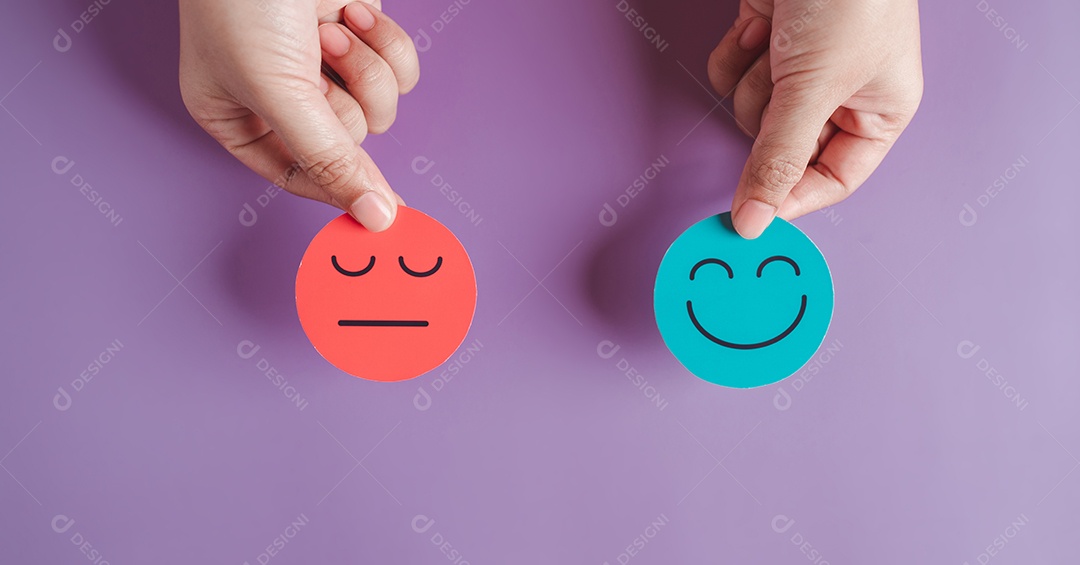 Duas mãos segurando rosto triste e rosto sorridente feliz, bipolar e depressão, conceito de saúde mental