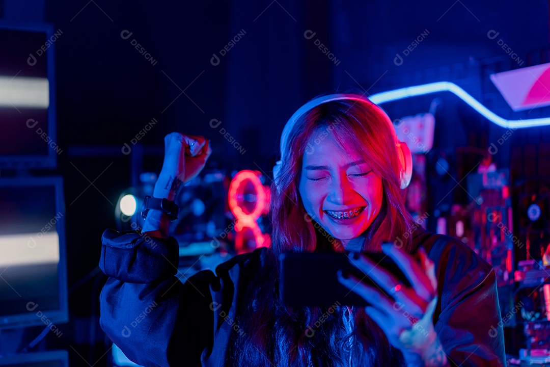 Jogadores felizes jogando videogame online com telefone celular inteligente com luzes de neon