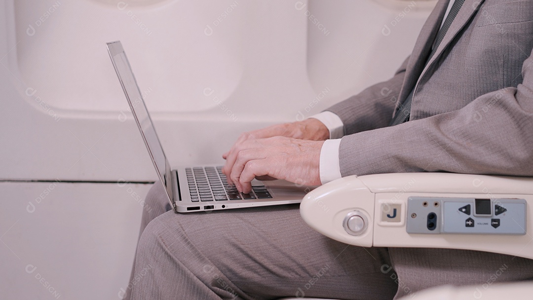 Empresário idoso bonito trabalhando com laptop digital no voo de avião