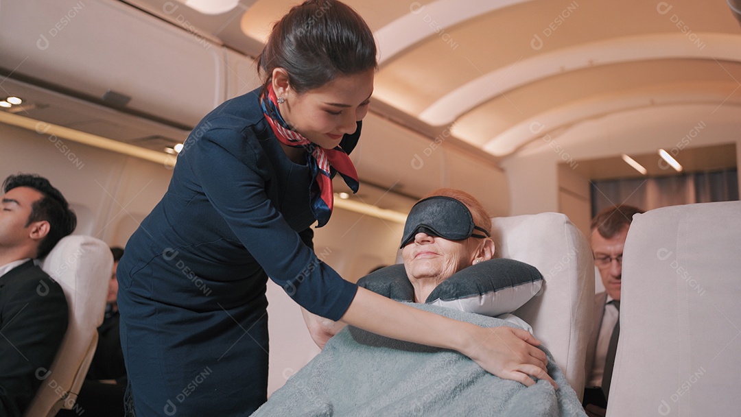 O comissário de bordo asiático cobre cobertores para passageiros idosos no voo de avião