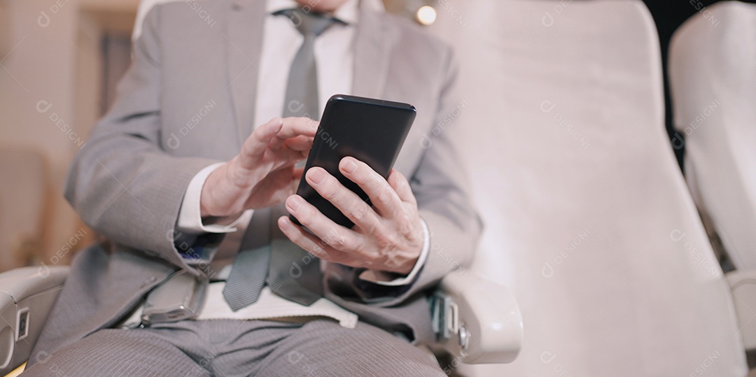 Empresário idoso bonito trabalhando com smartphone digital no voo de avião