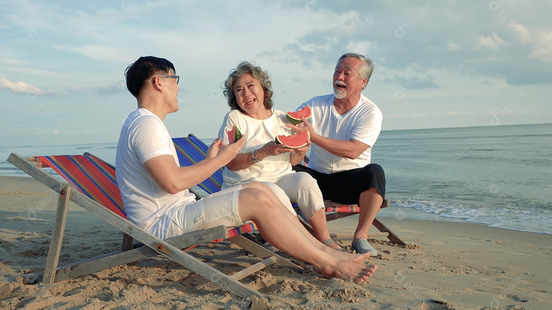 Felicidade, família asiática, filho e casal comendo frutas de melancia na praia