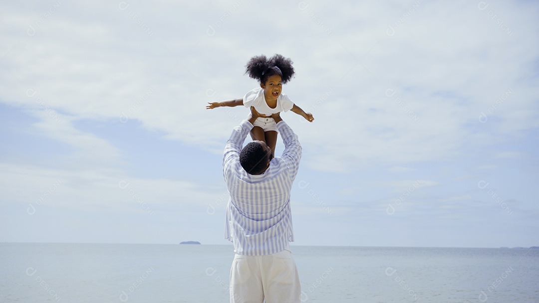 Pai afro-americano brincando com a filha juntos na praia férias de verão