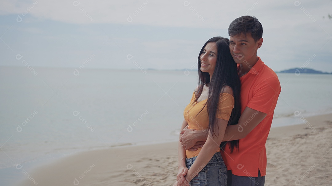 Casal jovem e mulher namorando olhando o mar na praia