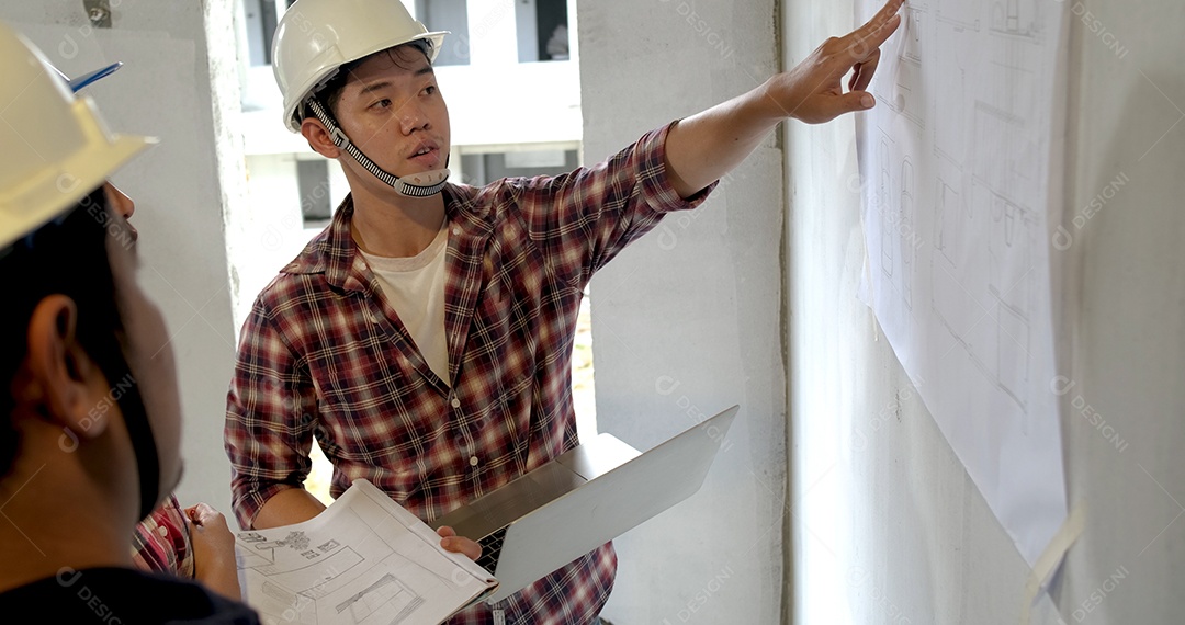 Grupo de jovens asiáticos de arquitetos de construção civil têm reuniões e debates juntos na parede