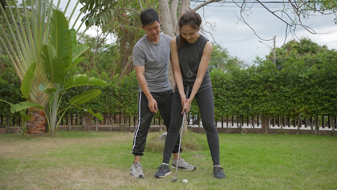 Casais asiáticos felizes jogando golfe juntos no campo