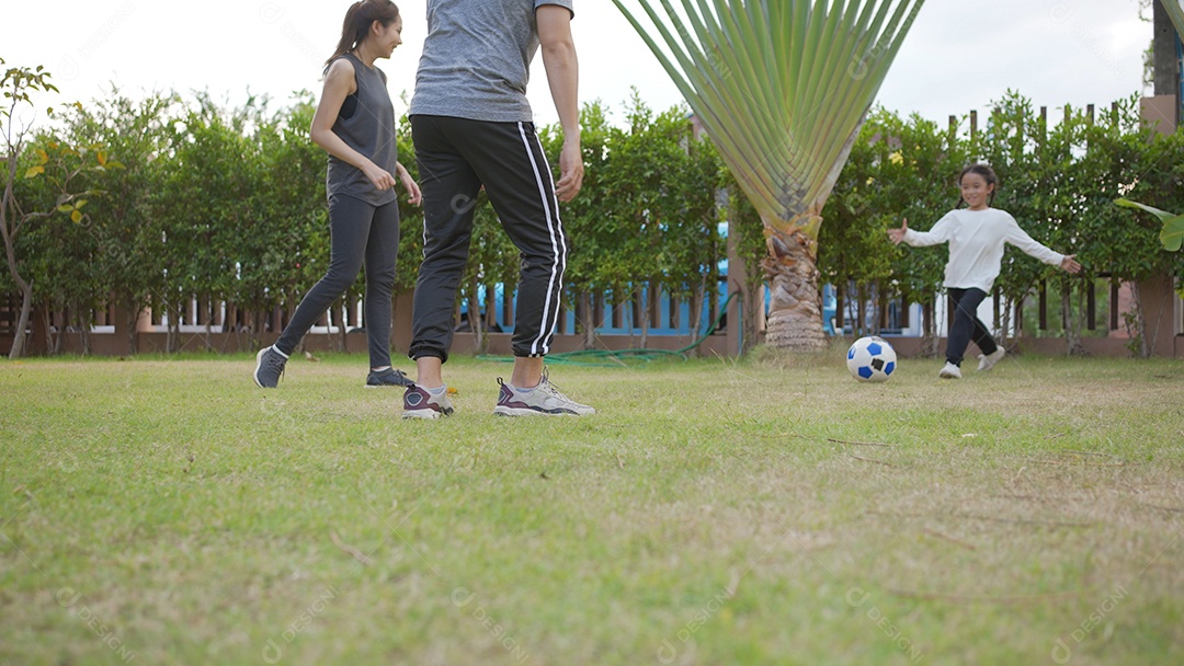 Feliz família asiática com crianças jogando futebol com a filha se divertindo juntas ao ar livre