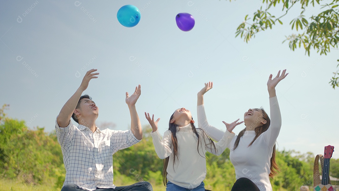 Mãe asiática e família feliz jogando balão e se divertimos