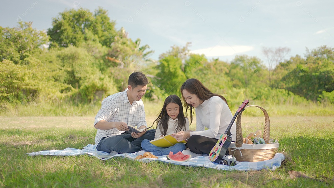 Feliz família asiática com garotinha aprendendo livro juntos e nos divertimos juntos durante um piquenique