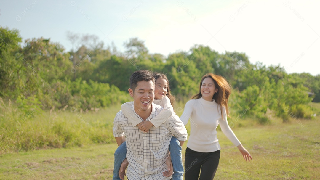 Feliz jovem pai asiático pegando carona com sua filhinha enquanto a mãe corre para brincar com ela