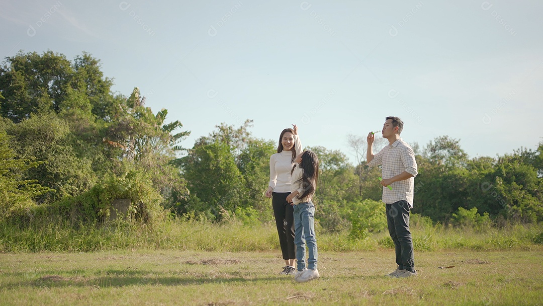 Feliz jovem pai asiático pegando carona com sua filhinha enquanto a mãe corre para brincar com ela no parque