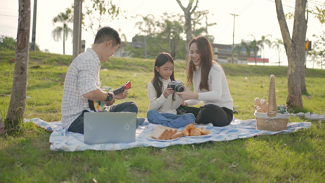 Feliz família asiática e pai está tocando Ukulele enquanto os pequenos tiram uma foto e se divertem