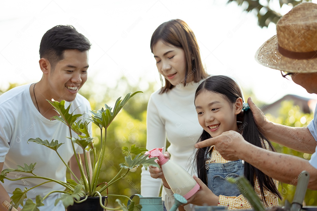 Casal asiático com filha jardinando enquanto assiste laptop juntos no jardim do quintal.