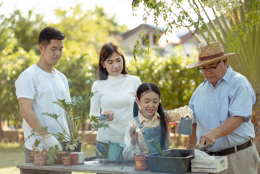 Casal asiático com filha jardinando enquanto assiste laptop juntos no jardim do quintal.