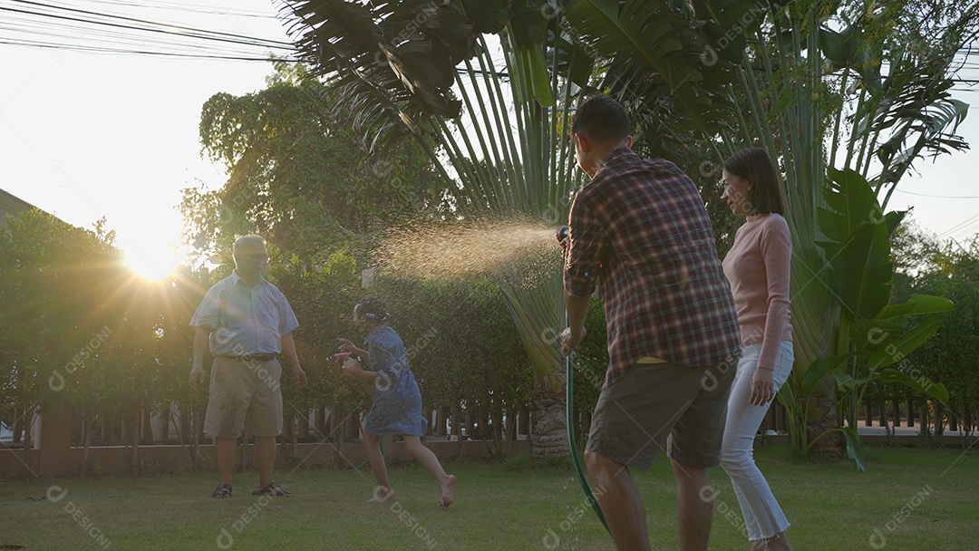 Feliz vovô sênior asiático derramando água de uma mangueira.