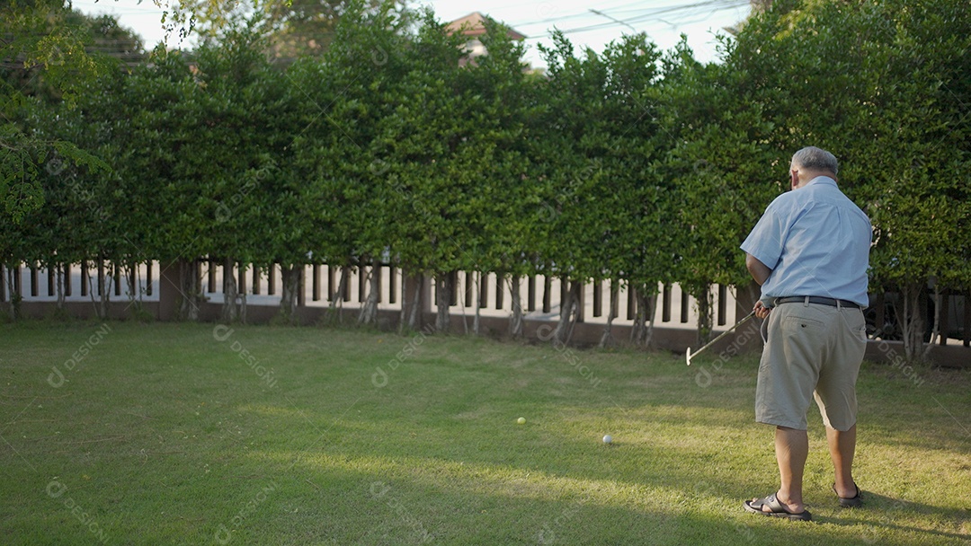 Sênior masculino de um jogador de golfe medindo sua próxima tacada no jardim ao fundo ao pôr do sol