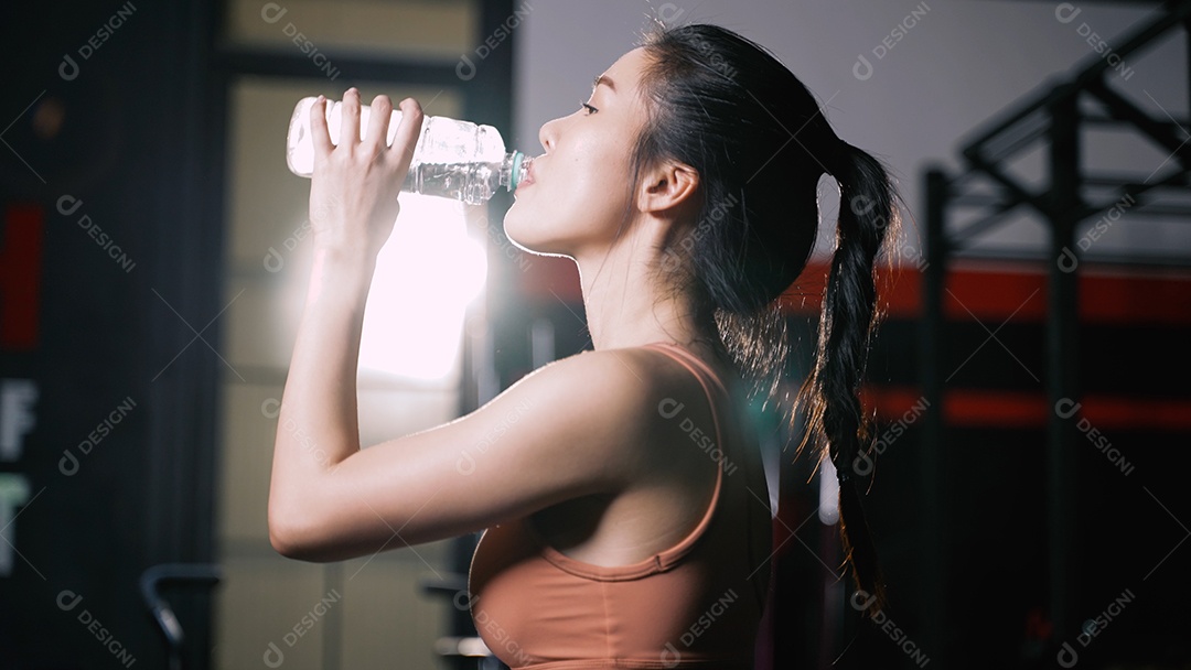 Atleta mulher asiática bebendo água pura após exercícios de treino