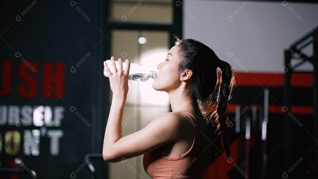 Atleta mulher asiática bebendo água pura após exercícios de treino