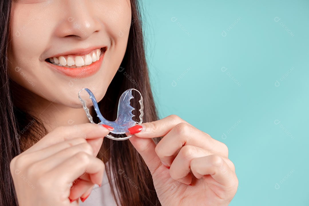 Sorriso bonito dental da jovem mulher asiática com aparelho retentor