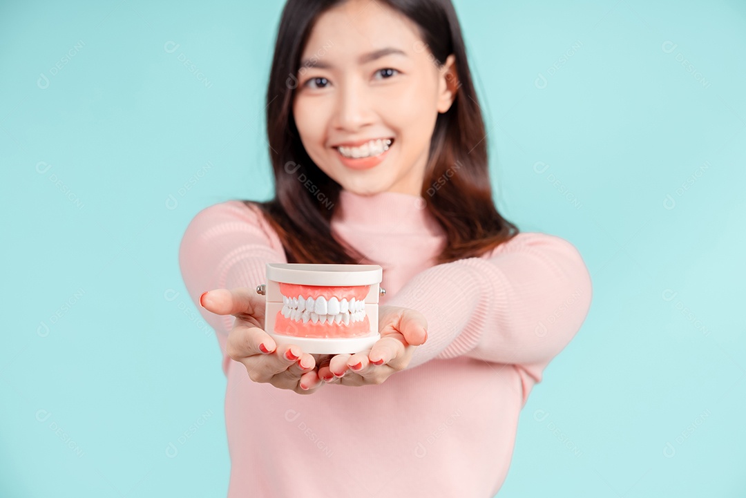 Odontologia da mulher asiática com amostra de dente e dentes brancos