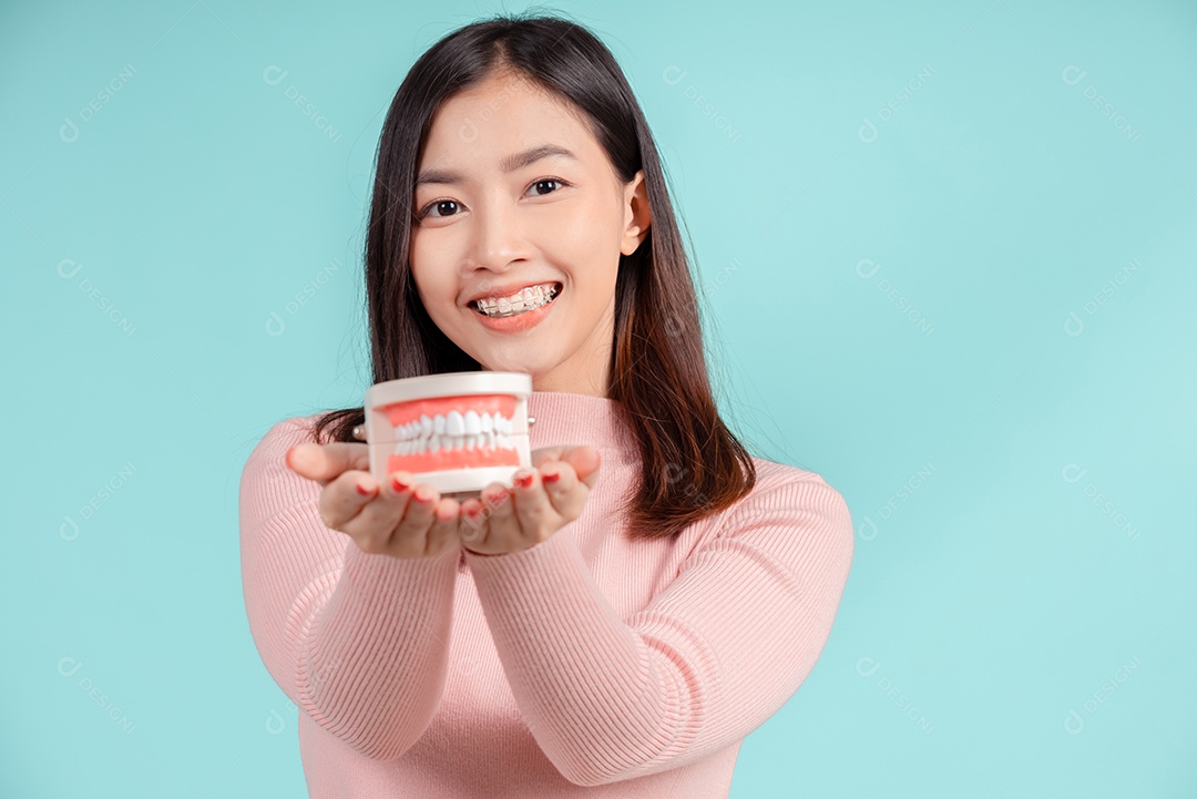 Odontologia da mulher asiática com amostra de dente e dentes brancos