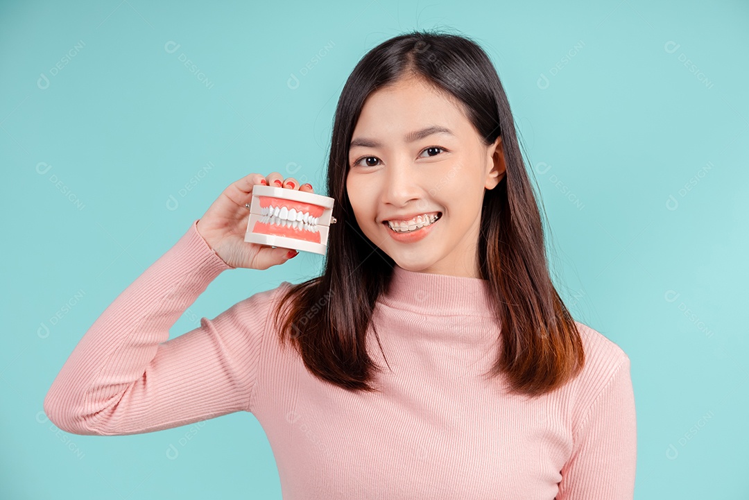 Odontologia da mulher asiática com amostra de dente e dentes brancos