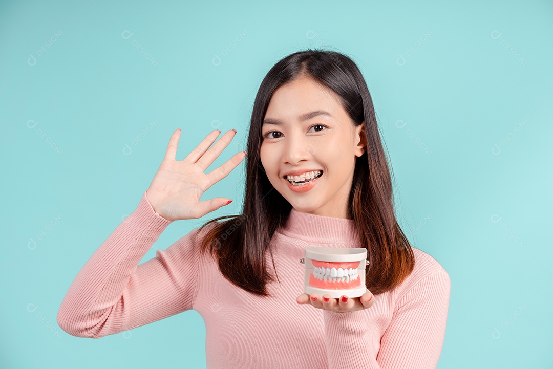 Odontologia da mulher asiática com amostra de dente e dentes brancos