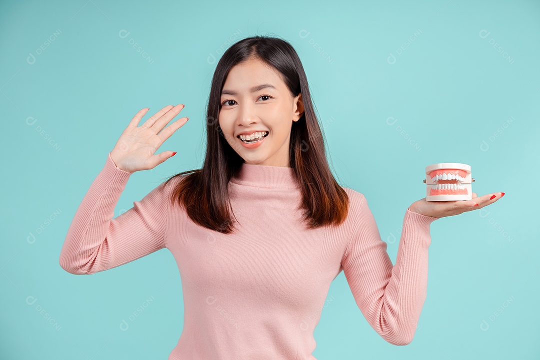 Odontologia da mulher asiática com amostra de dente e dentes brancos