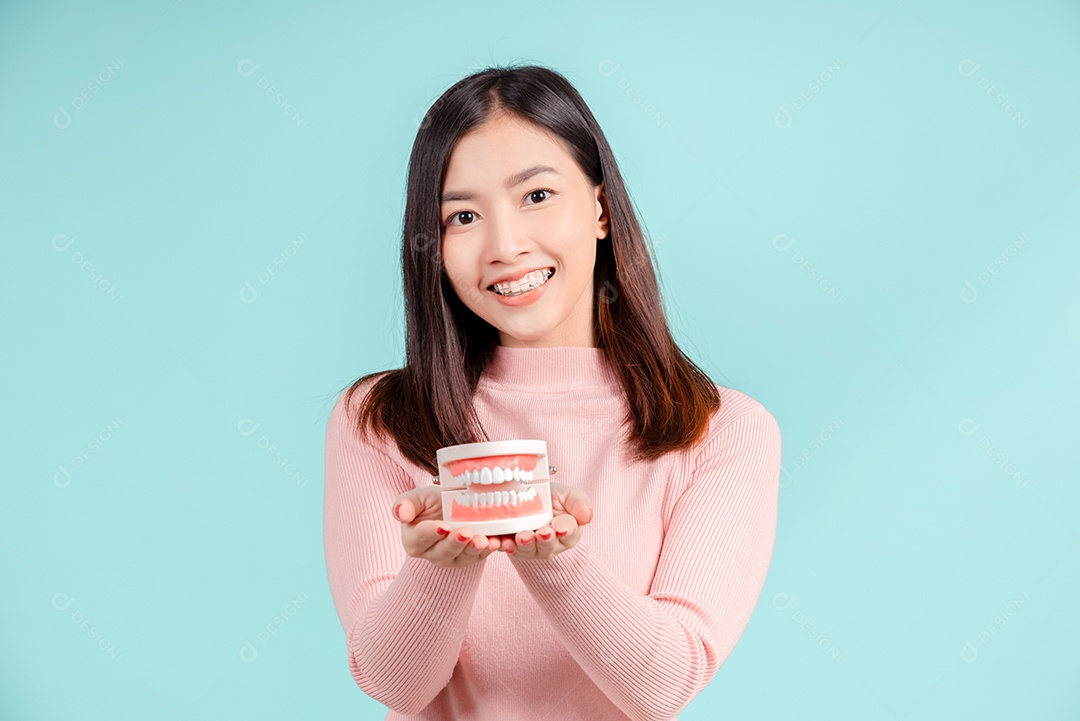 Odontologia da mulher asiática com amostra de dente e dentes brancos