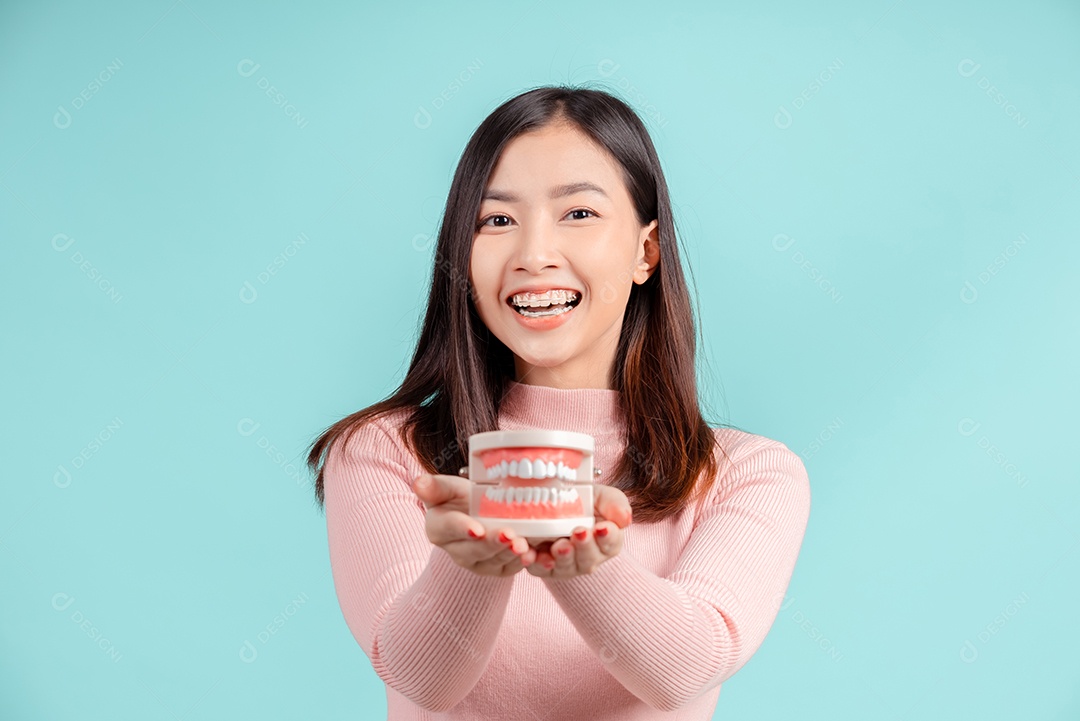 Odontologia da mulher asiática com amostra de dente e dentes brancos