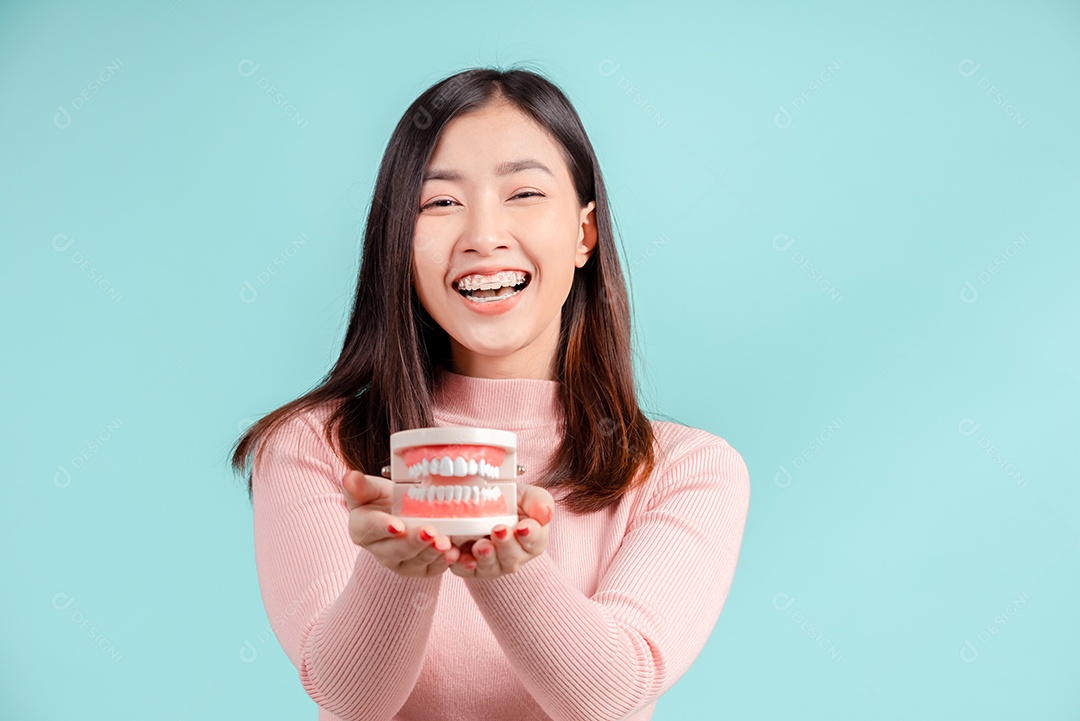 Odontologia da mulher asiática com amostra de dente e dentes brancos