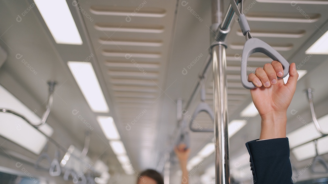 Mão de pessoas de negócios segura firmemente a alça ou o corrimão no skytrain ou no metrô