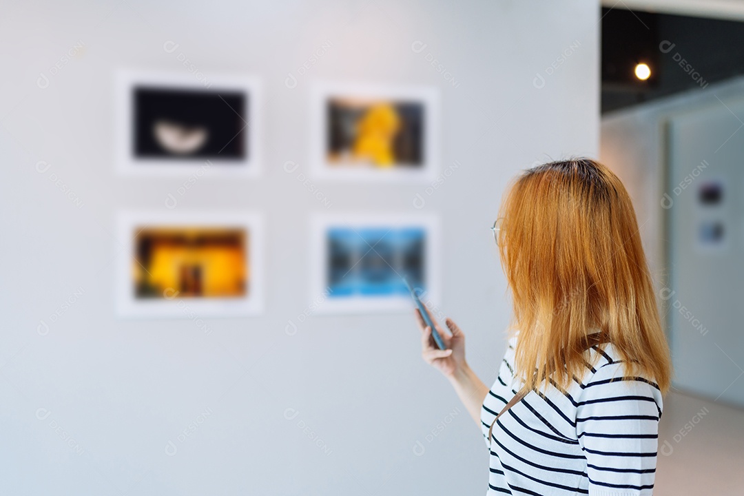 Mulher visitando a galeria de arte suas fotos olhando na parede, observando quadro