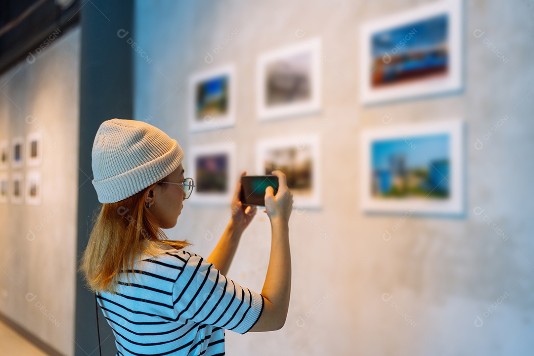 Mulher visitando a galeria de arte suas fotos olhando na parede, observando quadro