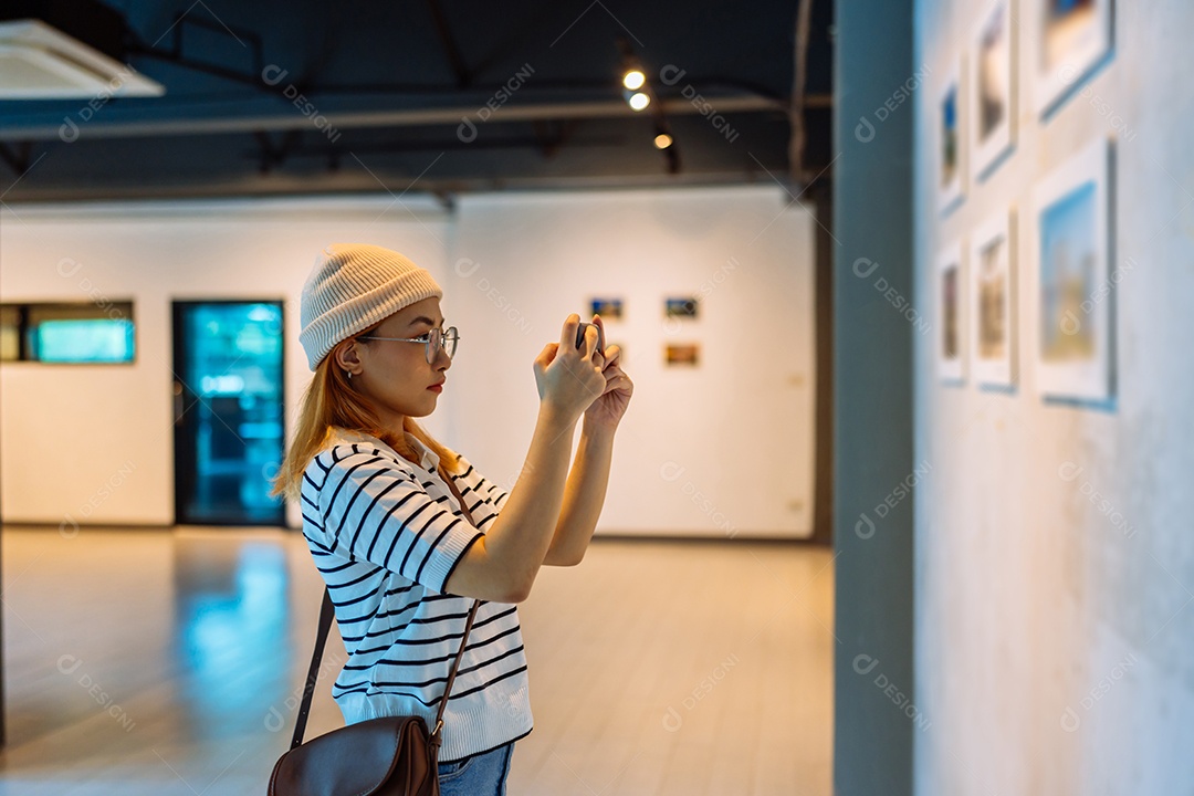 Mulher visitando a galeria de arte suas fotos olhando na parede, observando quadro