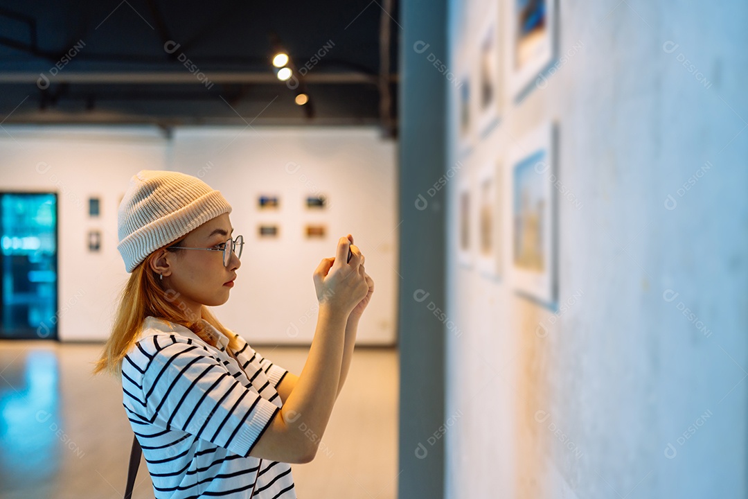 Mulher visitando a galeria de arte suas fotos olhando na parede, observando quadro