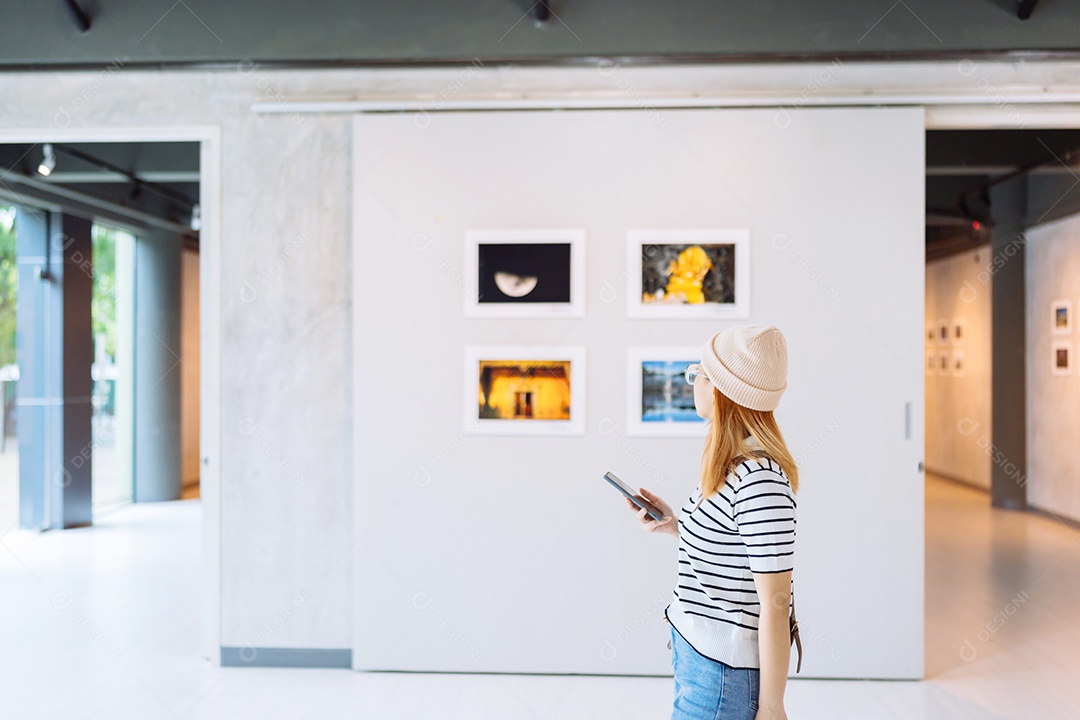 Mulher visitando a galeria de arte suas fotos olhando na parede, observando quadro