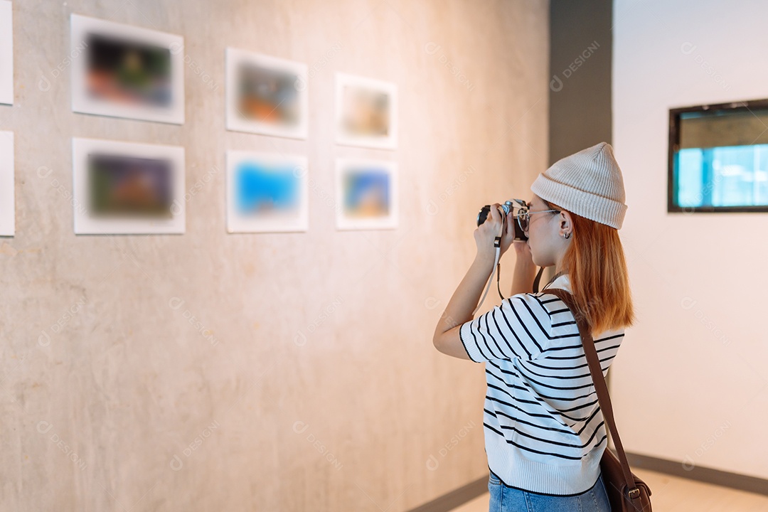 Mulher visitando a galeria de arte suas fotos olhando na parede, observando quadro