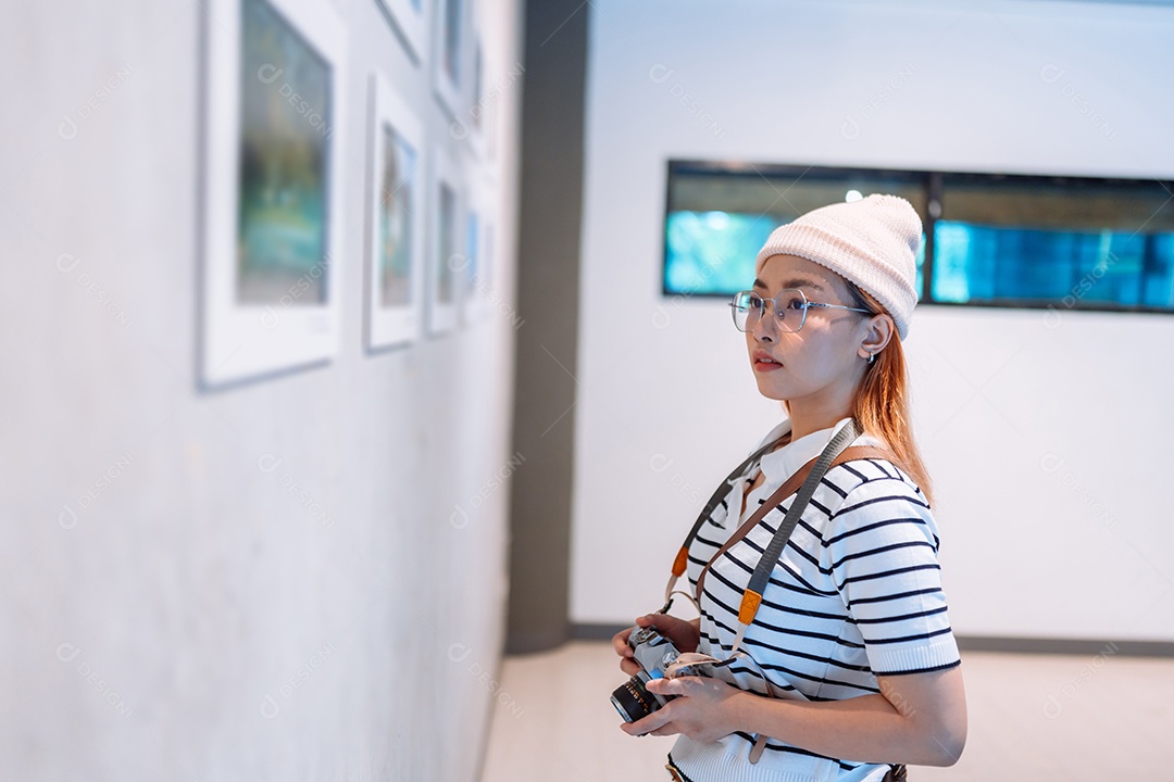 Mulher visitando a galeria de arte suas fotos olhando na parede, observando quadro