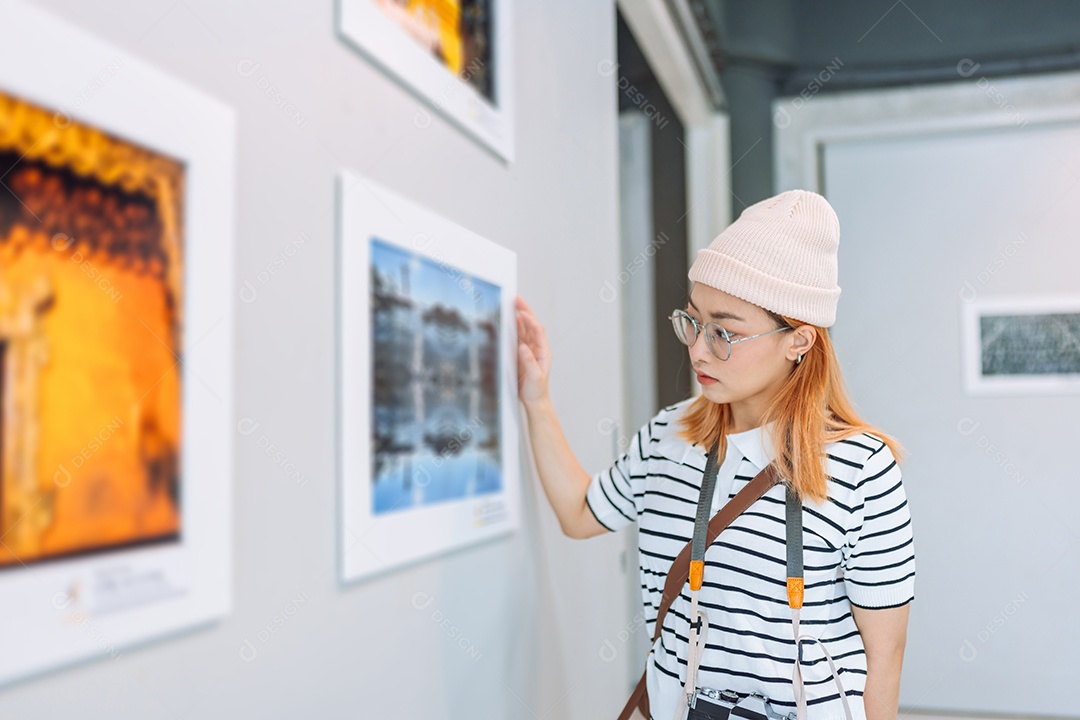 Mulher visitando a galeria de arte suas fotos olhando na parede, observando quadro