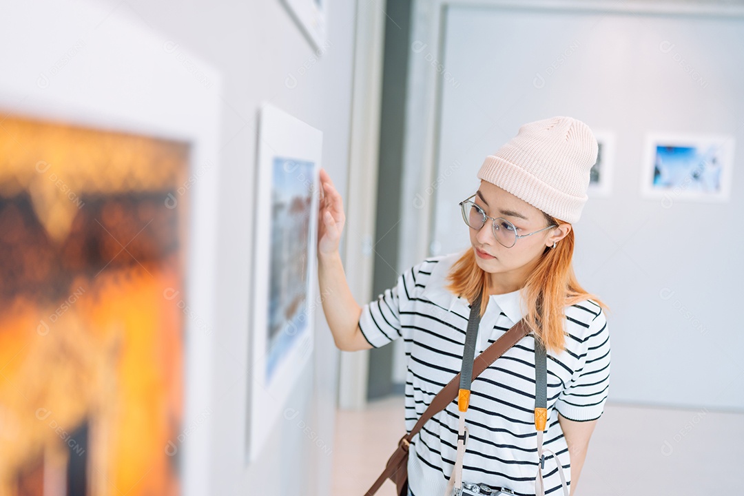 Mulher visitando a galeria de arte suas fotos olhando na parede, observando quadro