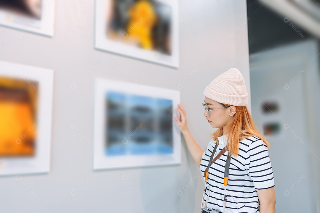 Mulher visitando a galeria de arte suas fotos olhando na parede, observando quadro