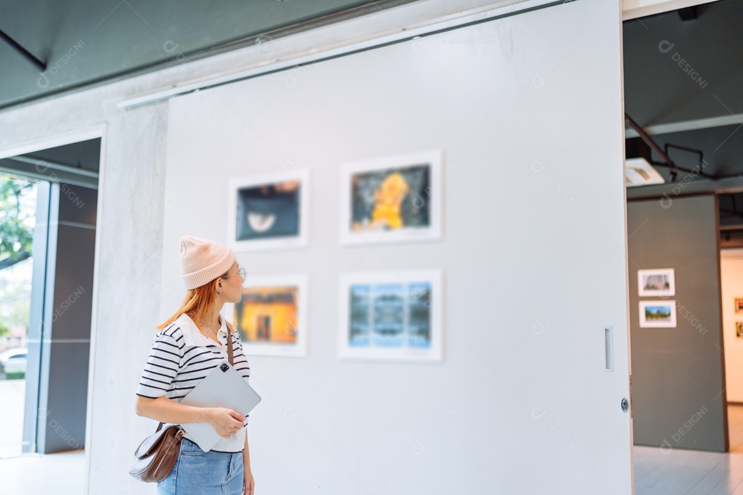 Mulher visitando a galeria de arte suas fotos olhando na parede, observando quadro