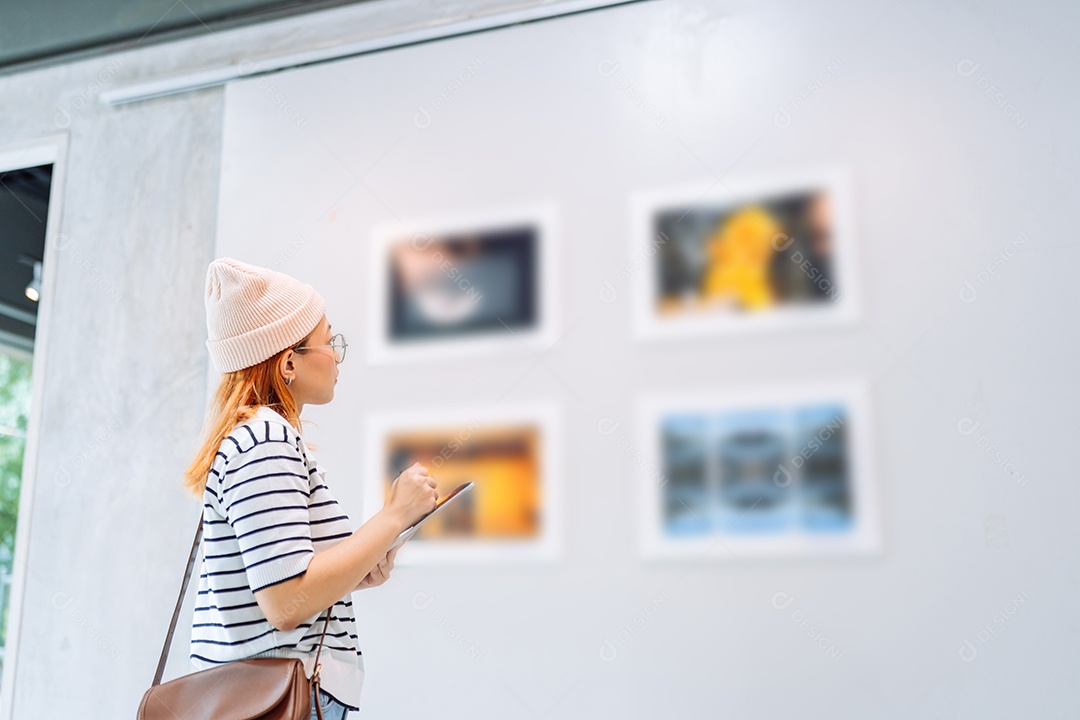 Mulher visitando a galeria de arte suas fotos olhando na parede, observando quadro