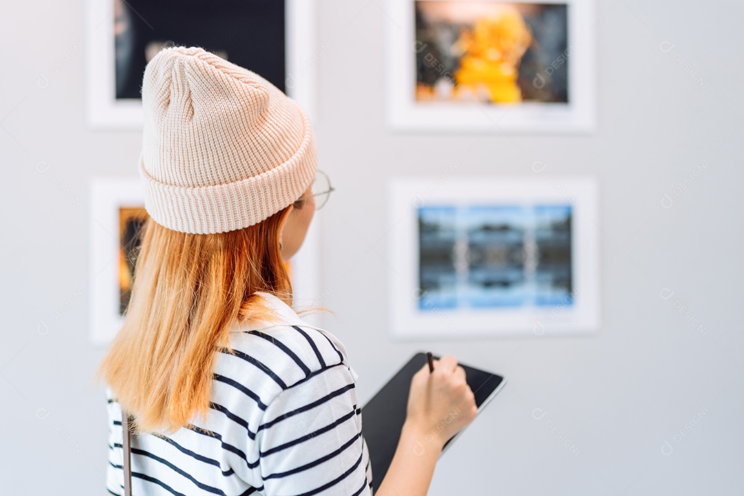 Mulher visitando a galeria de arte suas fotos olhando na parede, observando quadro