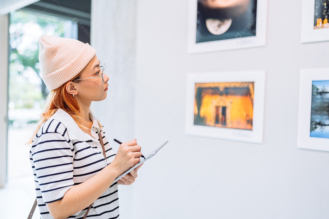 Mulher visitando a galeria de arte suas fotos olhando na parede, observando quadro