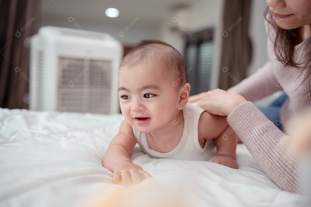 Mãe segurando bebê recém-nascido deitado em uma cama branca em casa.