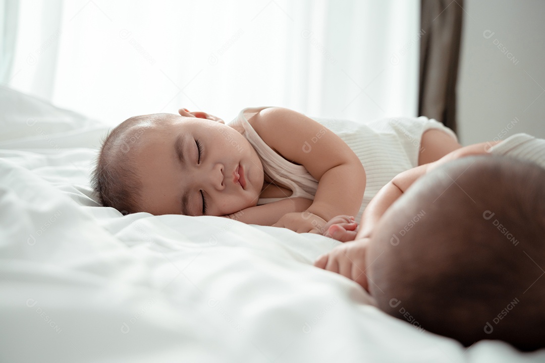 Bebês gêmeos recém-nascido deitado em uma cama branca em casa.